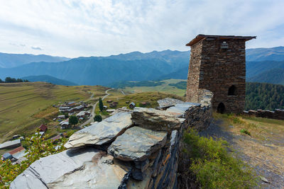 Old building by mountains against sky