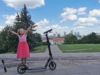 Woman riding bicycle in park against sky