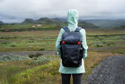 Woman with backpack and green jacket on travel in iceland