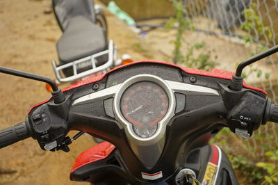 Close-up of wet motor scooter parked on field rainy season