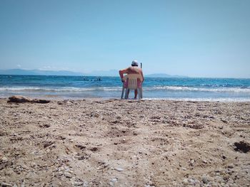 Rear view of man standing on beach against sky