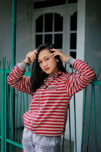 Young woman with arms raised standing against wall