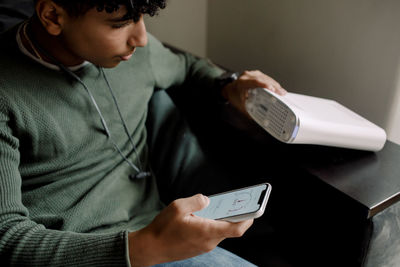 Teenage boy holding router while checking wi-fi connection on mobile phone at home