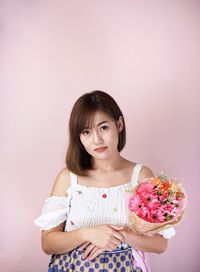 Portrait of woman standing against pink wall