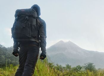 Rear view of man climbing on mountain against sky