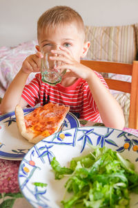 Close-up of cute of boy drinking water at home