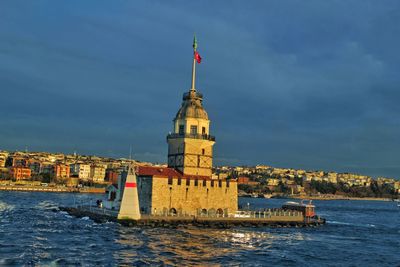 View of lighthouse in sea against buildings