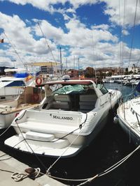 Sailboats moored at harbor against sky