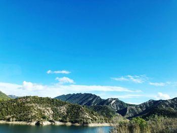 Scenic view of lake and mountains against blue sky