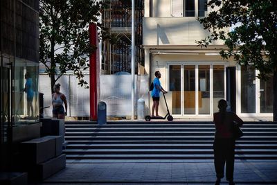 People walking on sidewalk by building in city