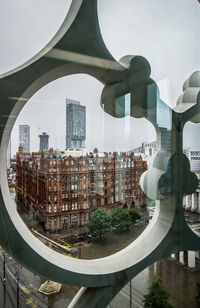 Buildings against sky seen through glass window