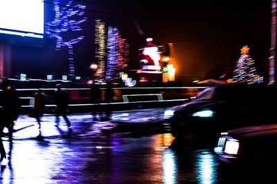 Illuminated wet car against sky at night