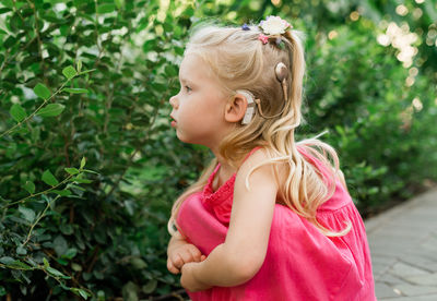 Side view of young woman standing against plants