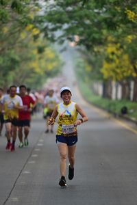 Rear view of people running on road