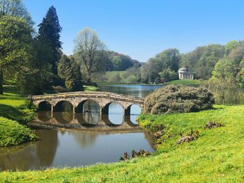 Arch bridge over river against trees and mountains