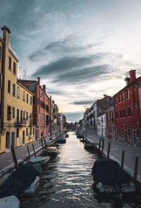 Canal amidst buildings in city against sky