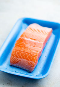 Fresh raw salmon in plastic container, close up view.