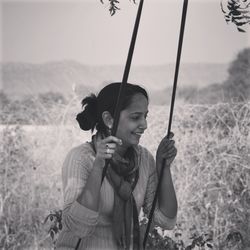 Young woman enjoying rope swing at field