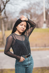 Young woman looking away while standing against tree