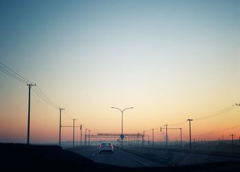 Cars on street against clear sky during sunset