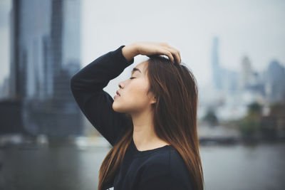 Portrait of young woman standing against blurred background