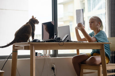 Teenage school boy student studying online on laptop near playful cat. online education, pet loved 