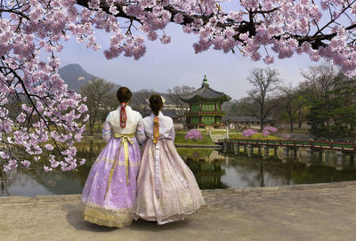 Rear view of women standing in traditional clothing against lake at park