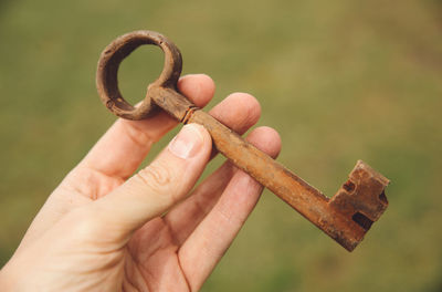 Cropped hand of person holding old-fashioned rusty metallic key