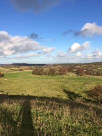 Scenic view of grassy landscape against cloudy sky