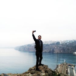 Full length of man using mobile phone against sky