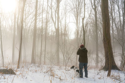 Rear view of man standing on snow covered field