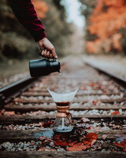 Cropped hand pouring water in coffee maker on railroad track