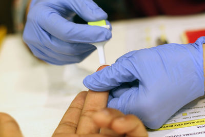 Cropped hands of doctor removing blood sample from patient finger