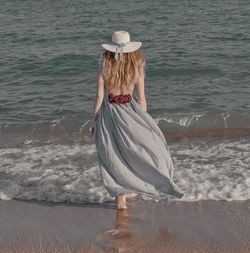 Rear view of woman with hat on beach