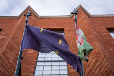 Low angle view of flag on building against sky