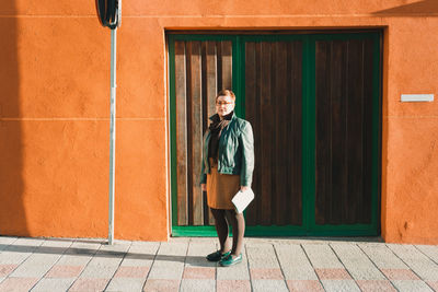 Full length of woman standing against closed door on sunny day