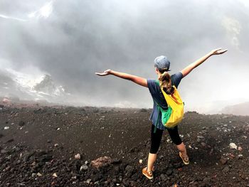 Young woman with arms outstretched against mountain