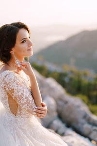 Young woman looking away while standing outdoors