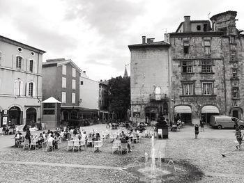 People on wet street against buildings in city