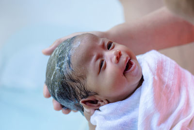 Cropped hands bathing baby girl at home