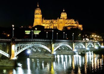 Illuminated bridge over river at night