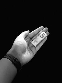 Close-up of hand holding text against black background