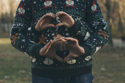 Midsection of father and child making heart shape with hands