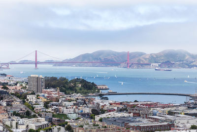 Suspension bridge over sea and buildings in city