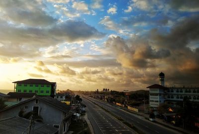 Cars on road in city against sky during sunset