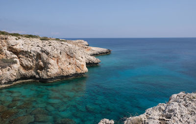 Rock formations in sea against clear sky