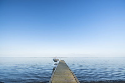 Pier over sea against clear blue sky