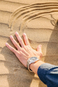 High angle view of hands on sand at beach