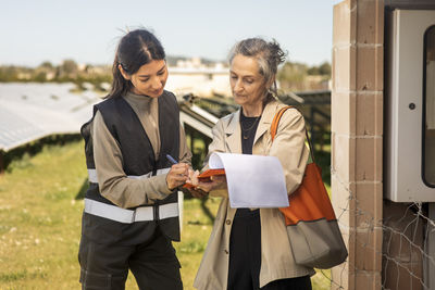 Female entrepreneur taking signature of engineer after visit at solar power station