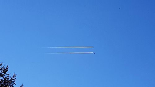 Low angle view of airplane flying against clear blue sky